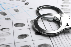 A piece of paper with finger prints taken from a criminal and also handcuffs.