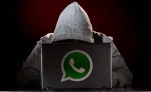 A person sitting behind a laptop accessing WhatsApp messages illegally.